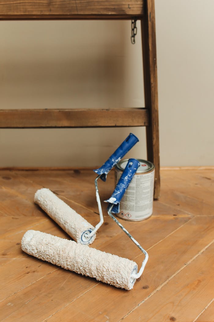 gallery-4 Paint rollers and can on a wooden floor, perfect for DIY home renovation projects.